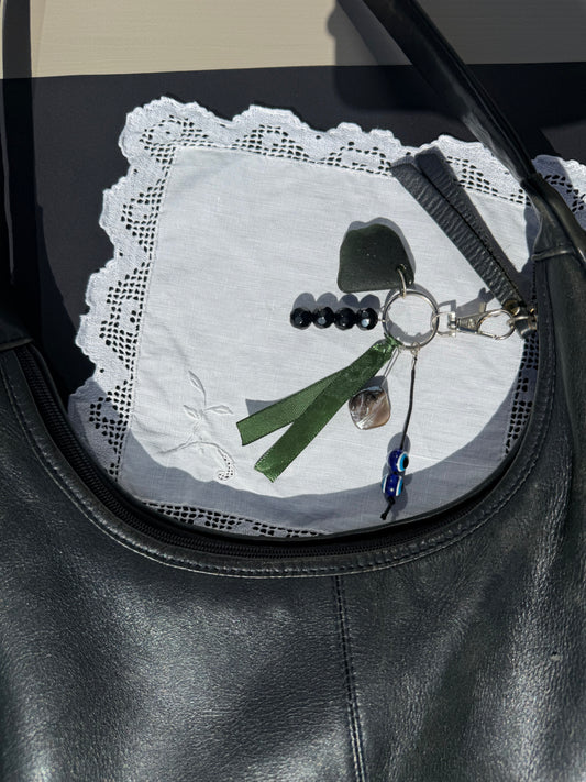 Keychain with green ribbon and decorative elements on a textured surface