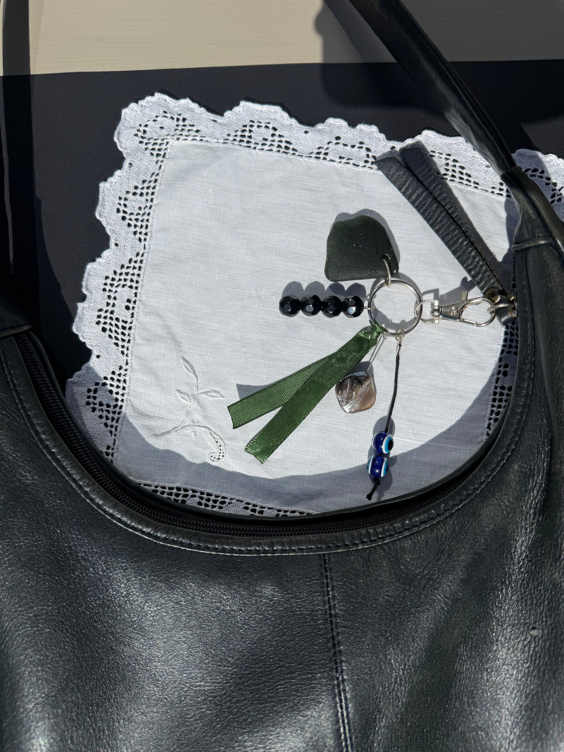 Keychain with green ribbon and decorative elements on a textured surface