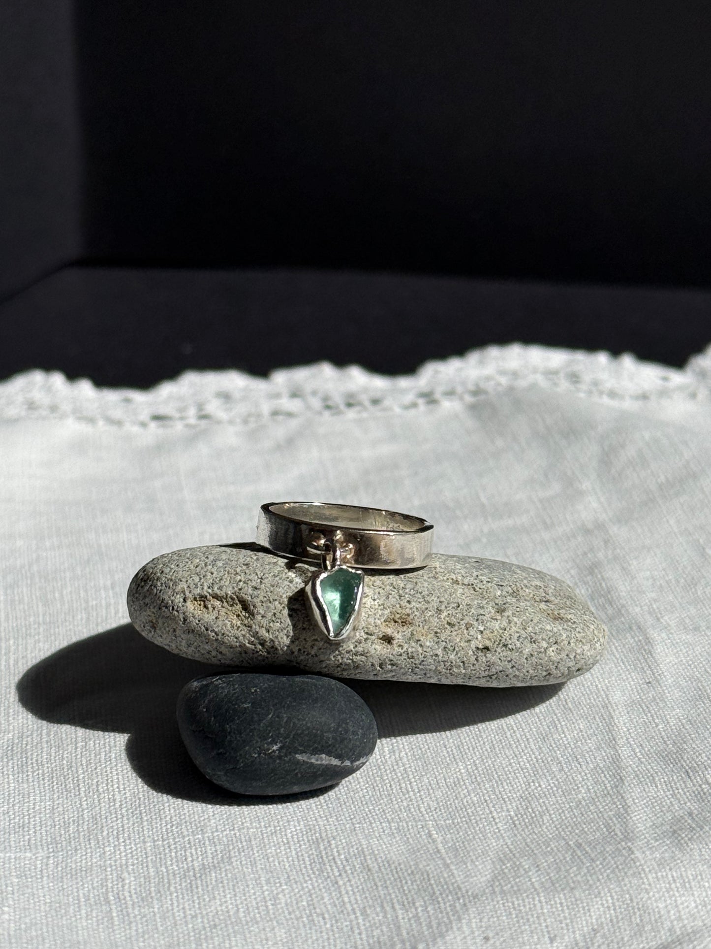 Silver ring with a green gemstone on a stone surface