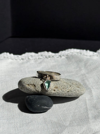 Silver ring with a green gemstone on a stone surface