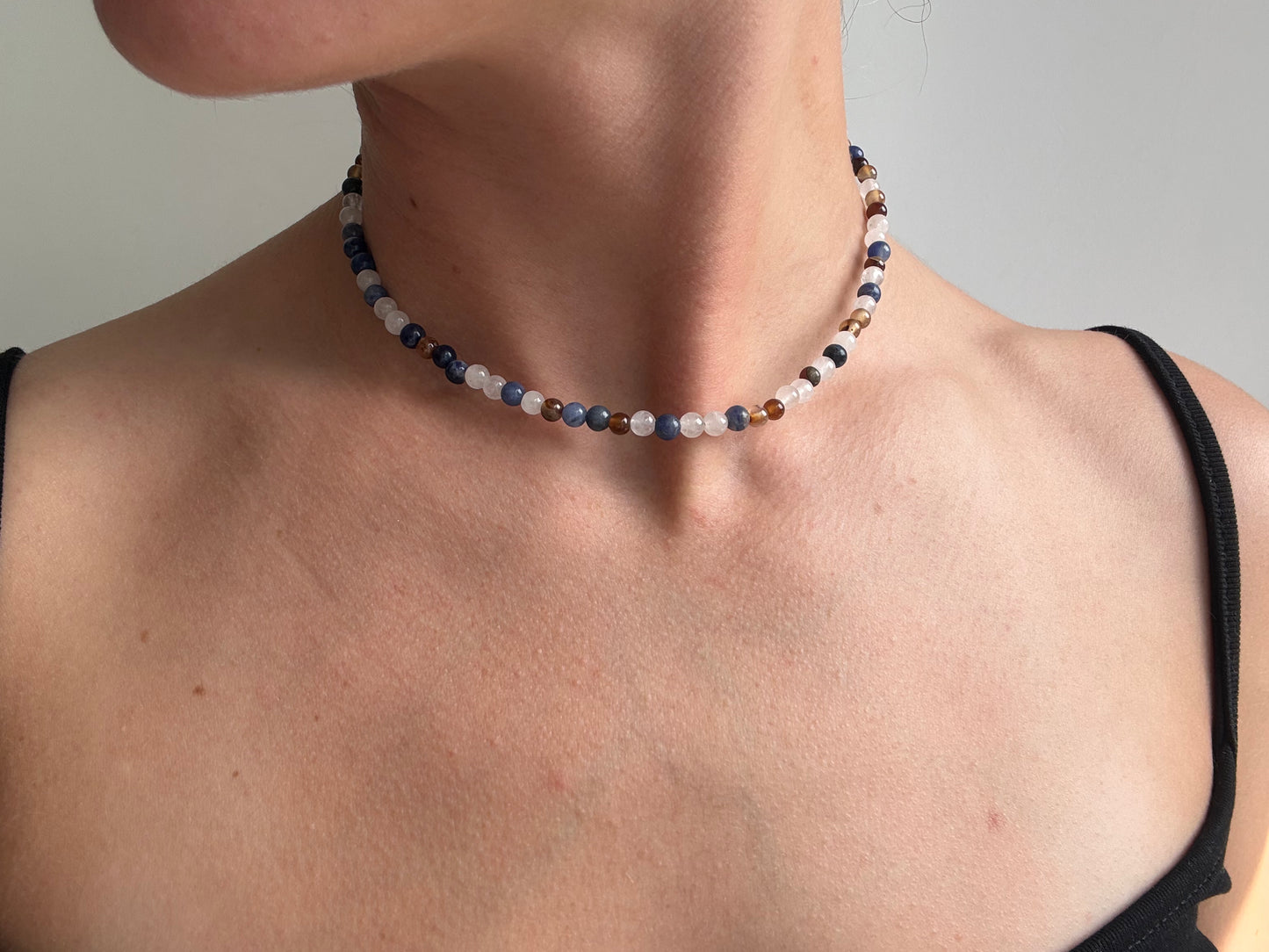 Necklace with multicolored beads worn by a person against a neutral background